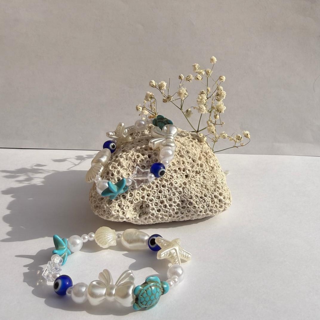 Blue Lagoon bracelet with blue ocean charms and pearls beside the rock