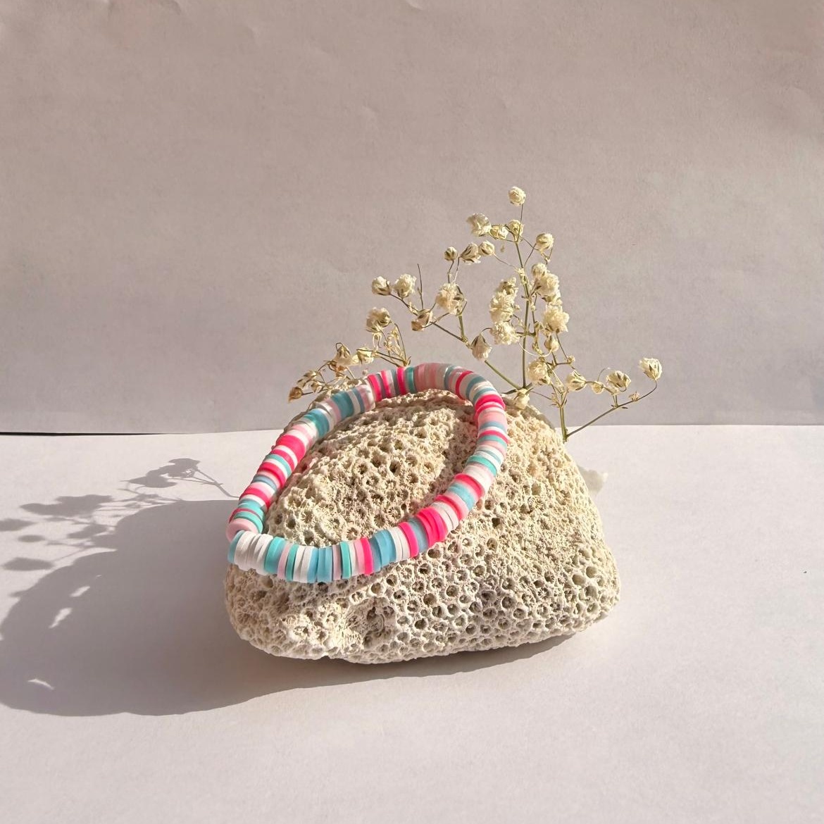 Bubblegum Party bracelet on a rock with flowers against a white background