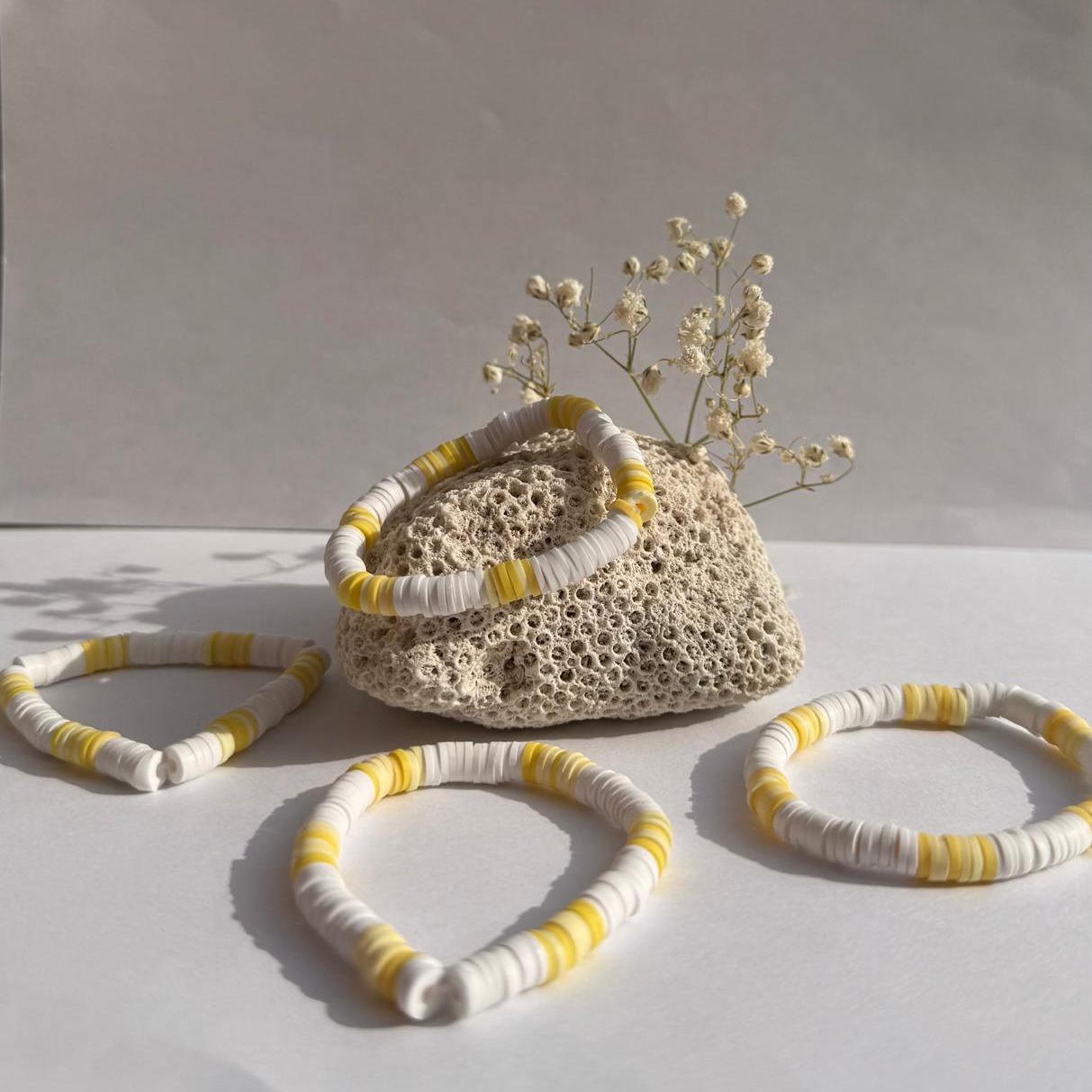 Lemon Drop bracelets arranged around a rock with white flowers