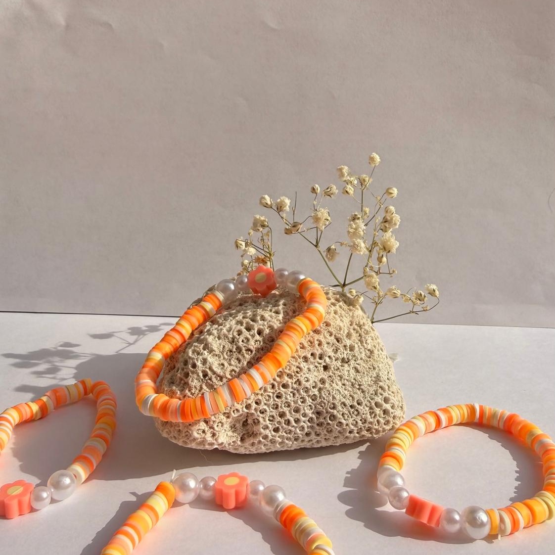 Peach Blossom bracelets around a rock with flowers against a white background