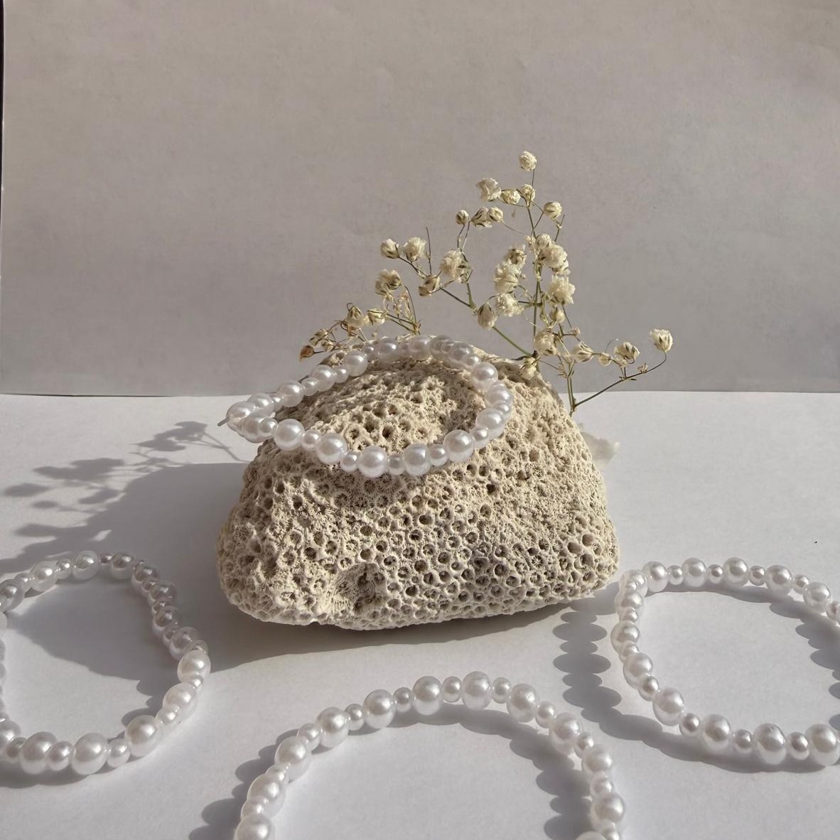 Pearl Pop bracelets arranged around a rock with white flowers