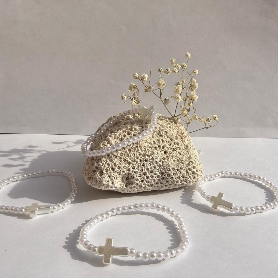 Pearl Prayer bracelets arranged around a rock with white flowers