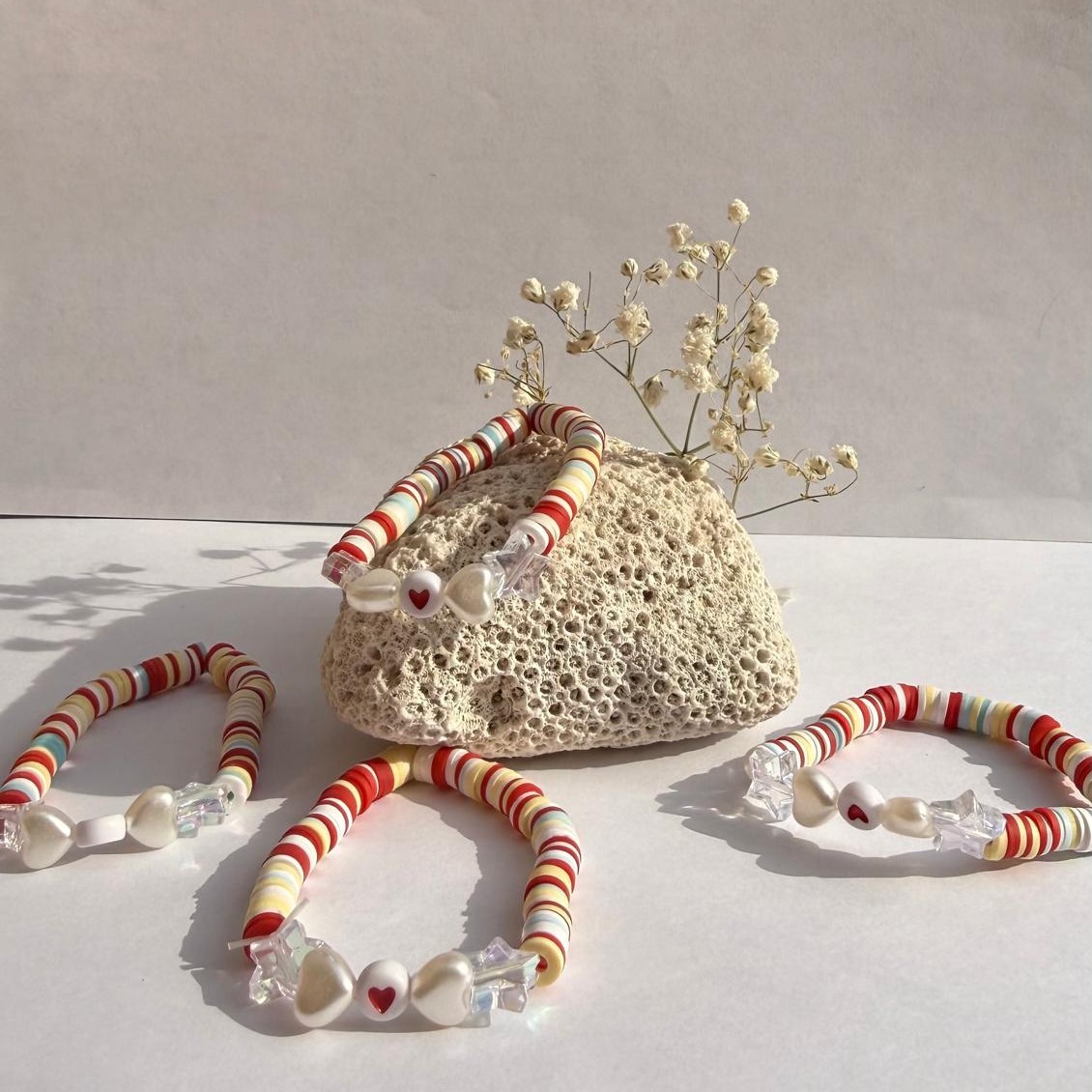 Red Ribbon bracelets arranged around a rock with white flowers