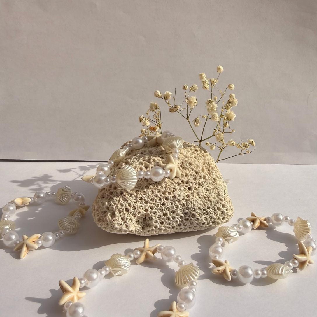 Starry Pearl bracelets around a rock with flowers against a white background