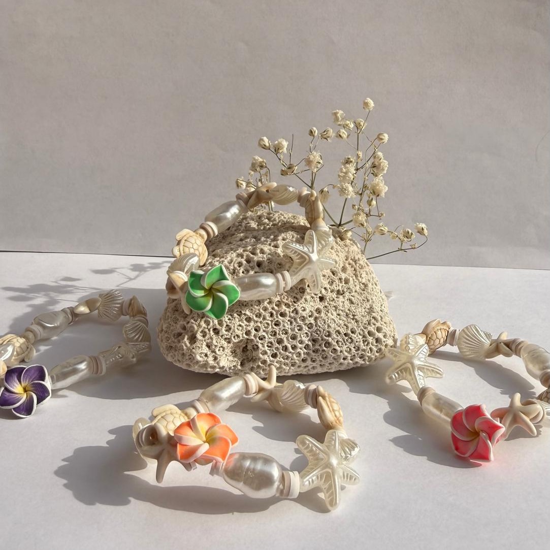 Turtle Blossom flower bracelets arranged around a rock with white flowers